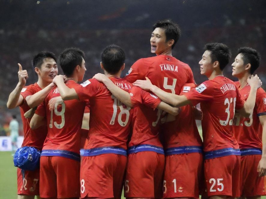 广州FC球迷在进球后狂热庆祝,手臂高举,脸上的笑容和汗水交织,背景是沸腾的看台和挥舞的旗帜,展现了足球的无限魅力。